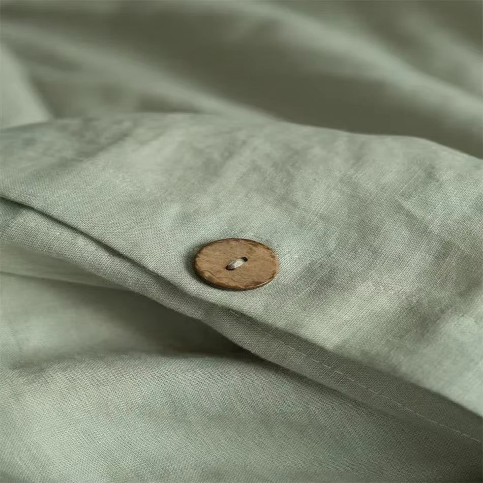 Gros plan sur un bouton en bois et la texture d'une housse de couette en lin vert amande