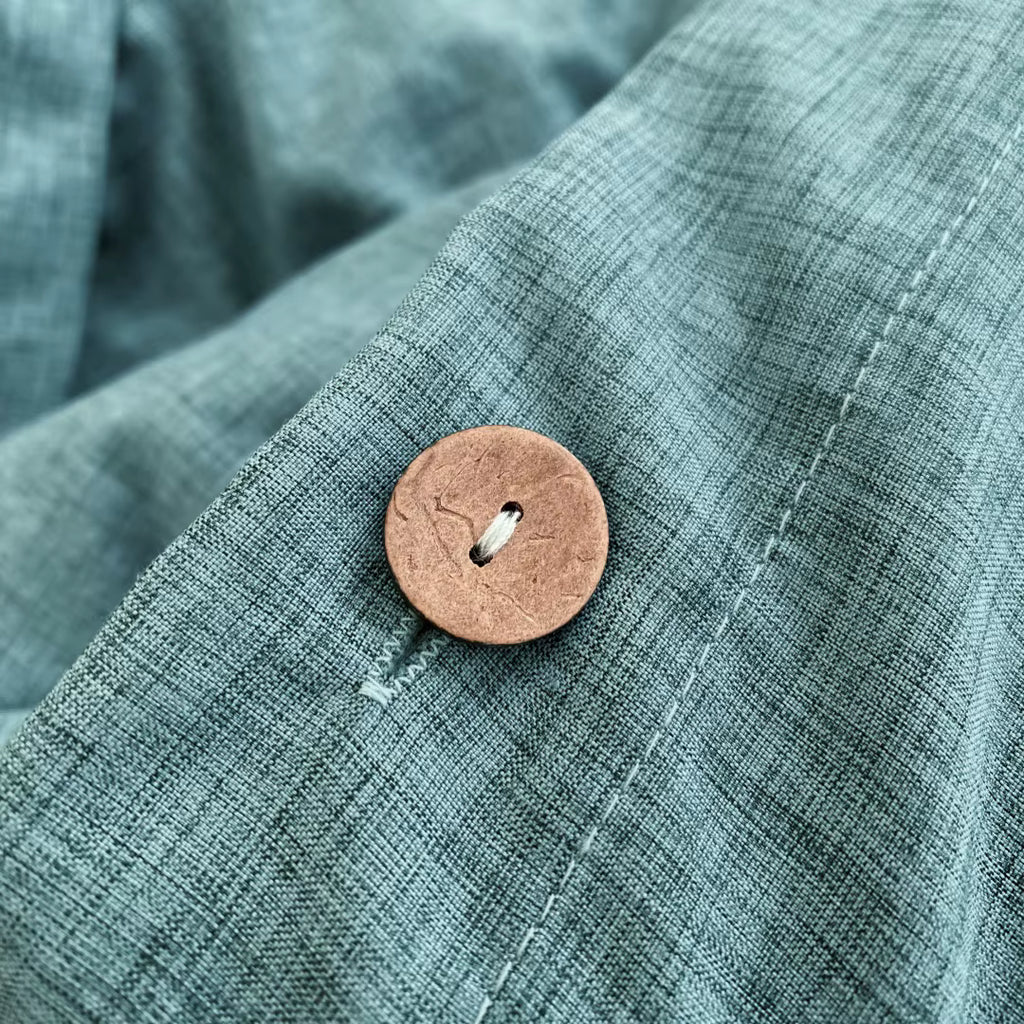 Gros plan sur un bouton et la texture d'une housse de couette en percale de coton vert canard