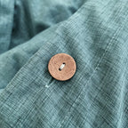 Gros plan sur un bouton et la texture d'une housse de couette en percale de coton vert canard