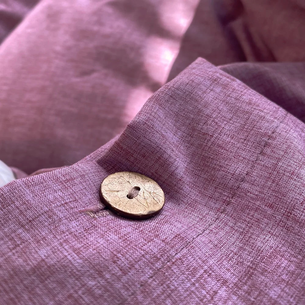 Gros plan sur un bouton et la texture d'une housse de couette en percale de coton violet raisin