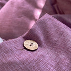 Gros plan sur un bouton et la texture d'une housse de couette en percale de coton violet raisin