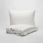 Housse de couette en lin blanc pliée, fermée par des boutons, avec taie d'oreiller assortie