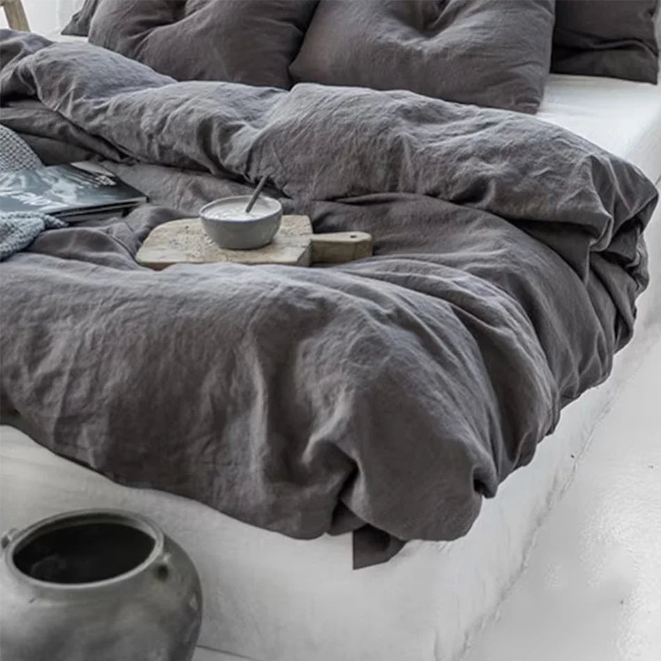 Housse de couette en lin gris anthracite froissé sur un lit aux draps blancs
