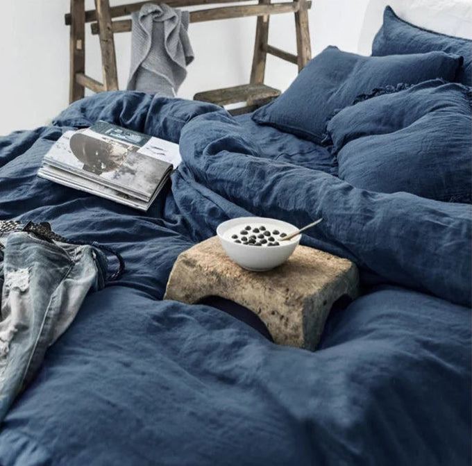 Housse de couette et taies d'oreiller en lin lavé bleu marine sur un lit défait