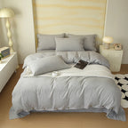 Housse de couette en percale de coton gris chiné à boutons sur un lit, avec taies assorties