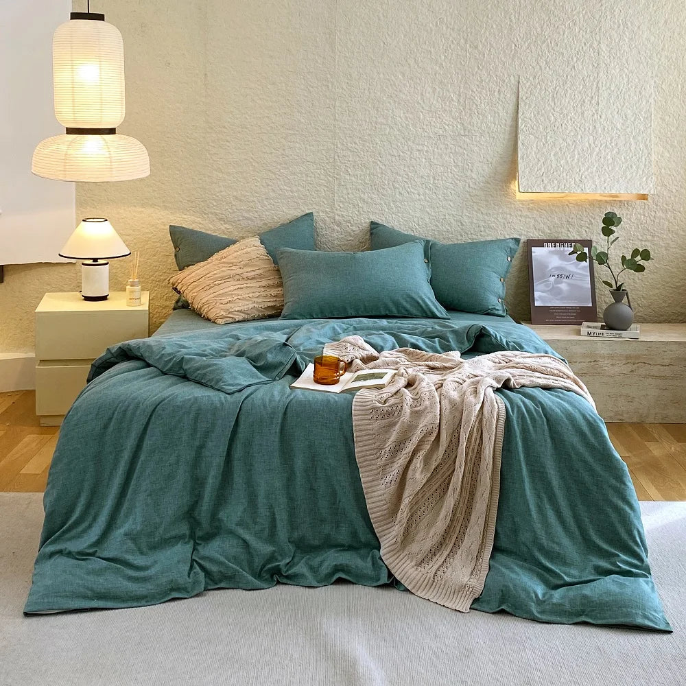Housse de couette et taies d'oreiller en percale de coton vert canard sur un lit, vue de face
