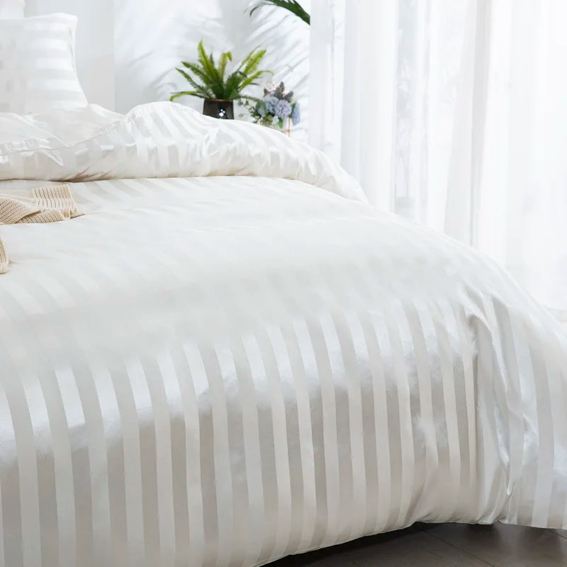 Vue de côté d'une housse de couette en satin blanc à rayures ton sur ton recouvrant un lit