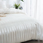 Vue de côté d'une housse de couette en satin blanc à rayures ton sur ton recouvrant un lit