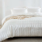 Housse de couette en satin blanc à rayures ton sur ton sur un lit, vue rapprochée avec taies