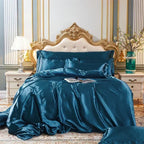 Housse de couette en satin bleu canard drapée sur un lit, vue de face avec taies assorties