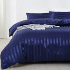 Housse de couette en satin bleu marine à rayures sur un lit, vue légèrement de côté avec taies