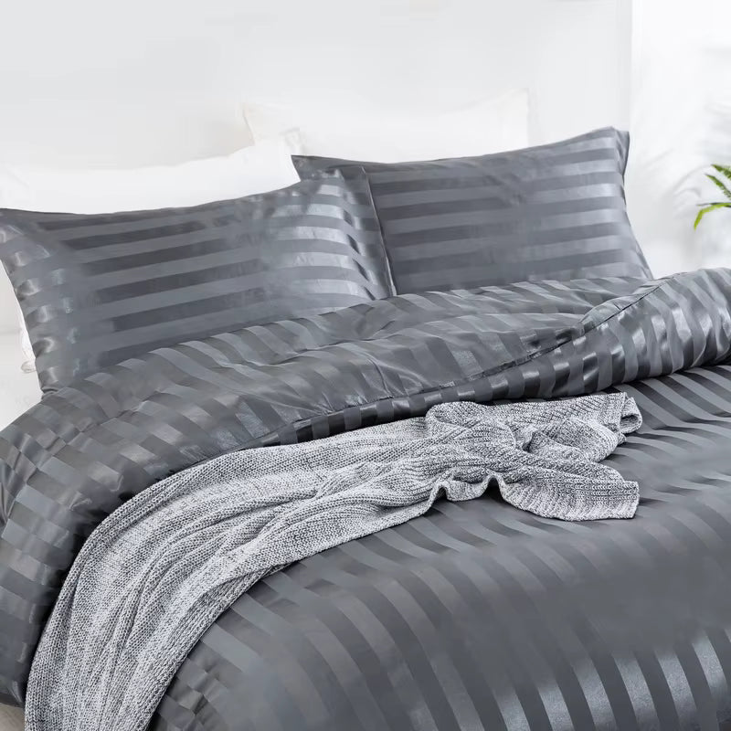 Housse de couette en satin gris anthracite à rayures sur un lit, vue de trois quarts avec taies