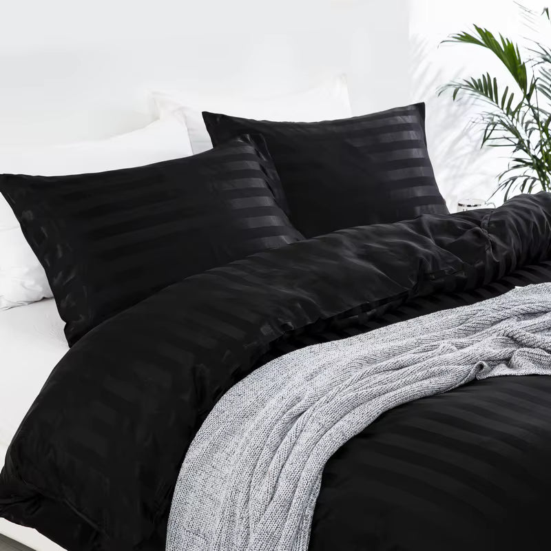 Vue rapprochée d'une housse de couette et de taies d'oreiller en satin noir à rayures ton sur ton