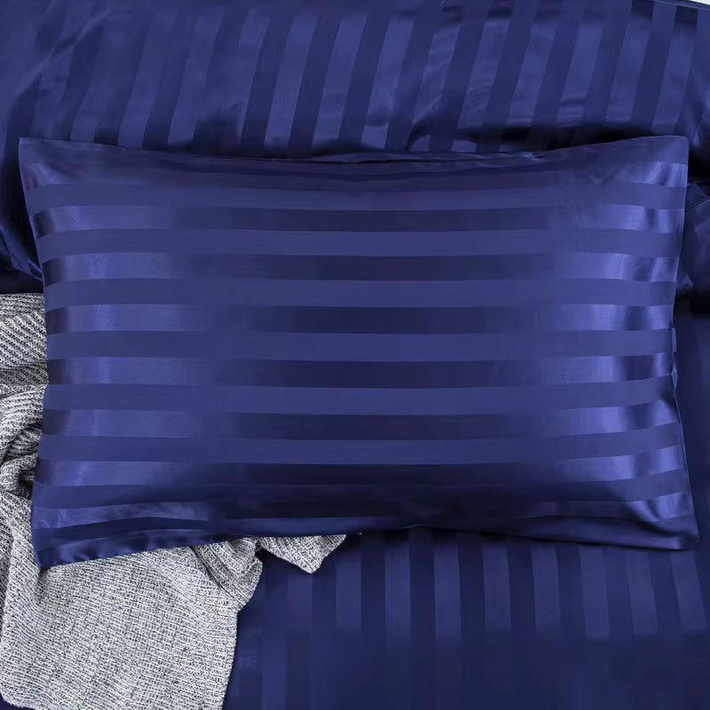 Taie d'oreiller en satin bleu marine à rayures ton sur ton posée sur la housse de couette assortie