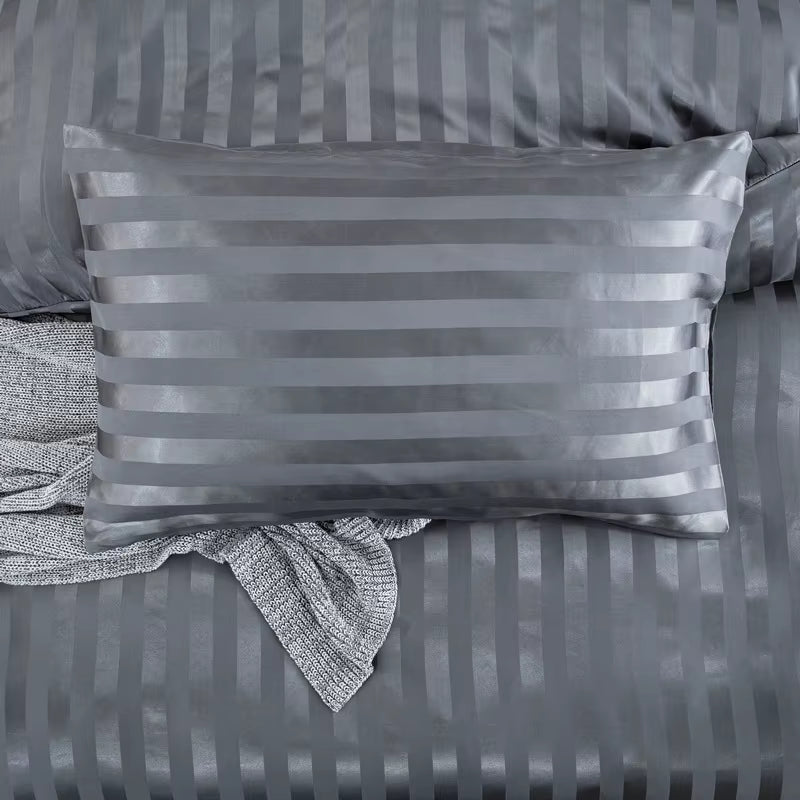 Taie d'oreiller en satin gris anthracite à rayures posée sur la housse de couette assortie
