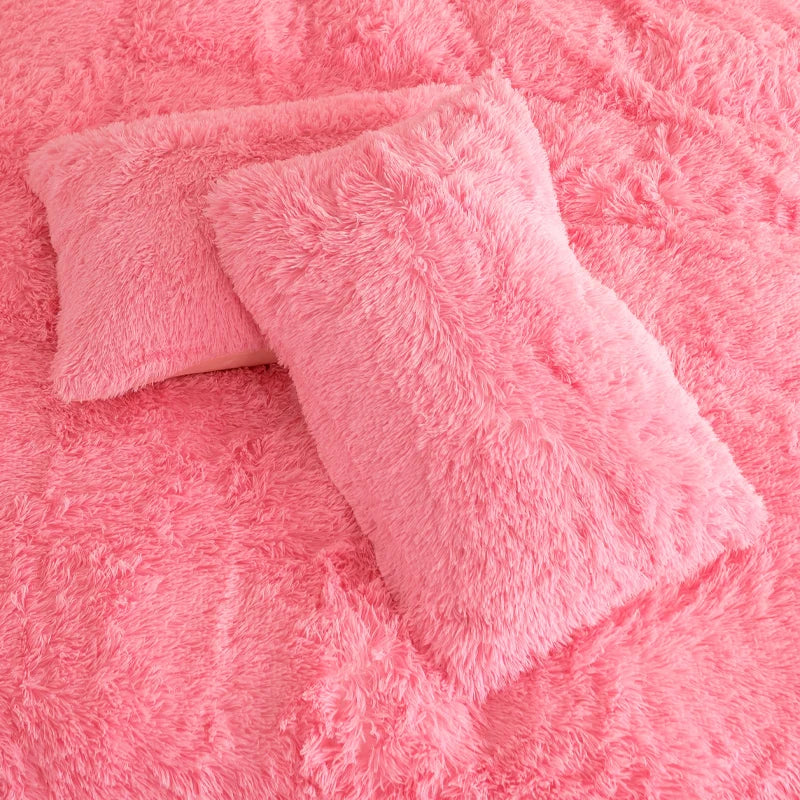 Deux taies d'oreiller effet fourrure rose à poils longs posées sur la housse de couette assortie