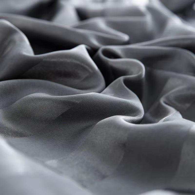 Gros plan sur les plis souples et brillants d'un tissu en satin gris anthracite