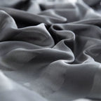 Gros plan sur les plis souples et brillants d'un tissu en satin gris anthracite